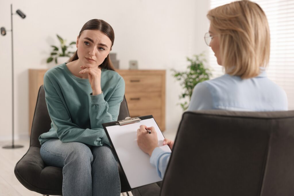 Postpartum mother consulting therapist during recovery session.
